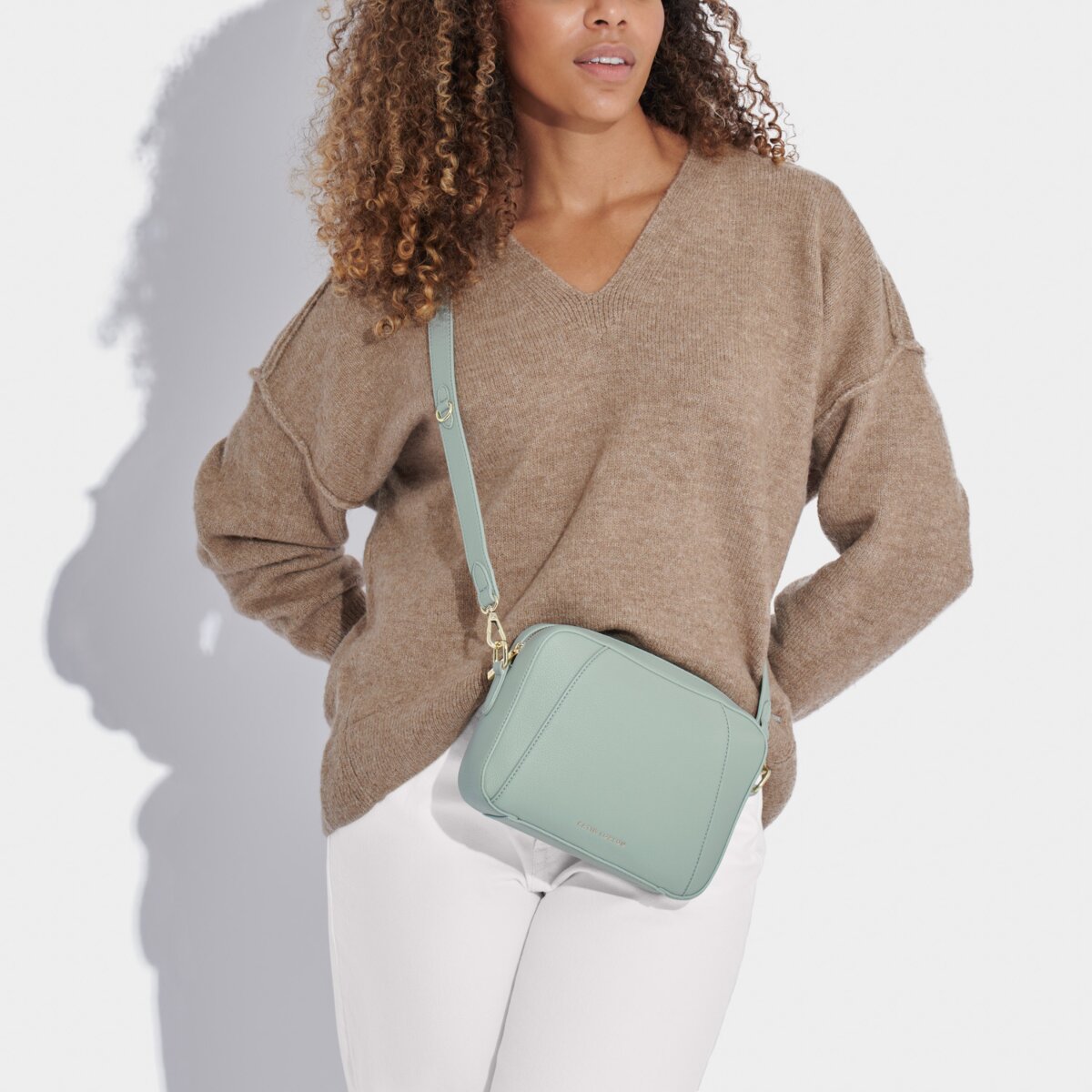 Model wearing white jeans and brown jumper with a duck egg blue crossbody handbag