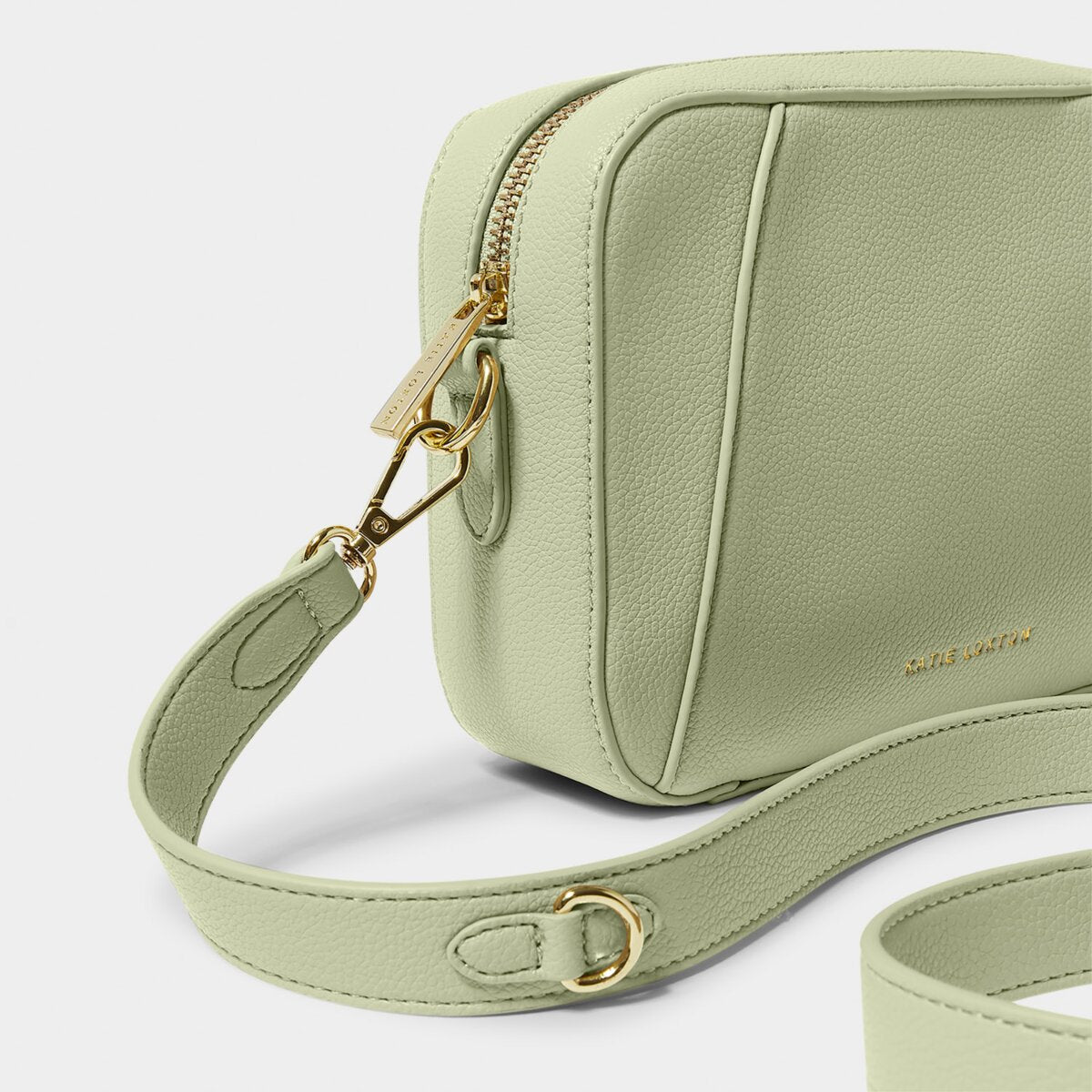 close up of a Crossbody handbag in soft sage greeen, focussing on the gold zipper and bag hardware