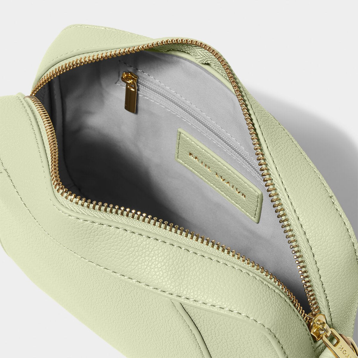 interior shot of a Crossbody handbag in soft sage greeen, highlighting the internal zipped pouch
