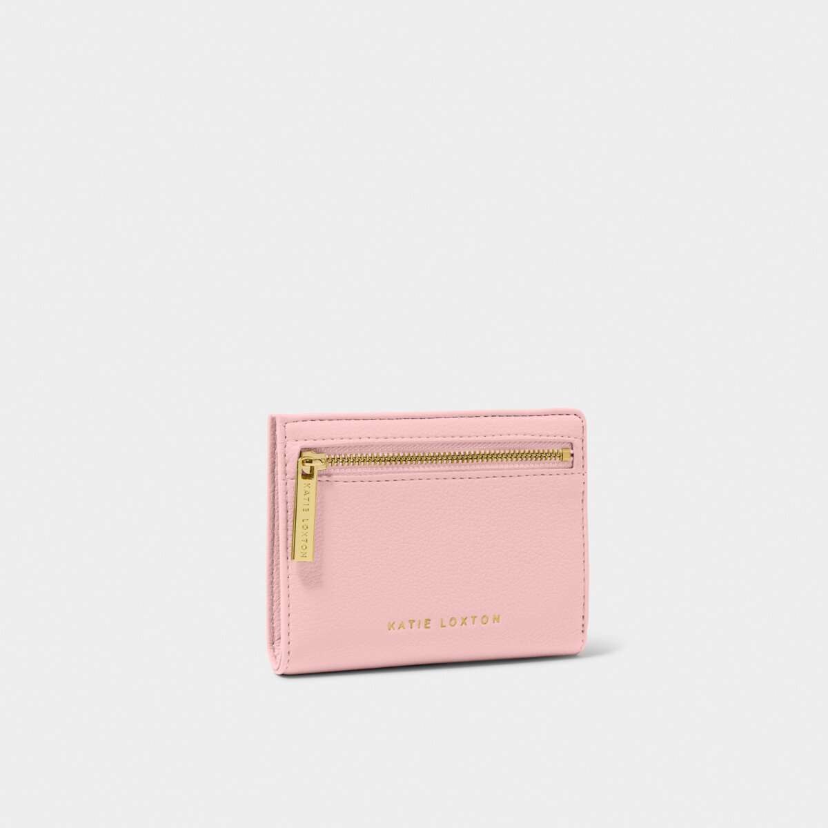 The Katie Loxton Jayde purse, which is a small rectangluar shape in baby pink with a gold zipper. The purse has Katie Loxton embossed in gold in small letters