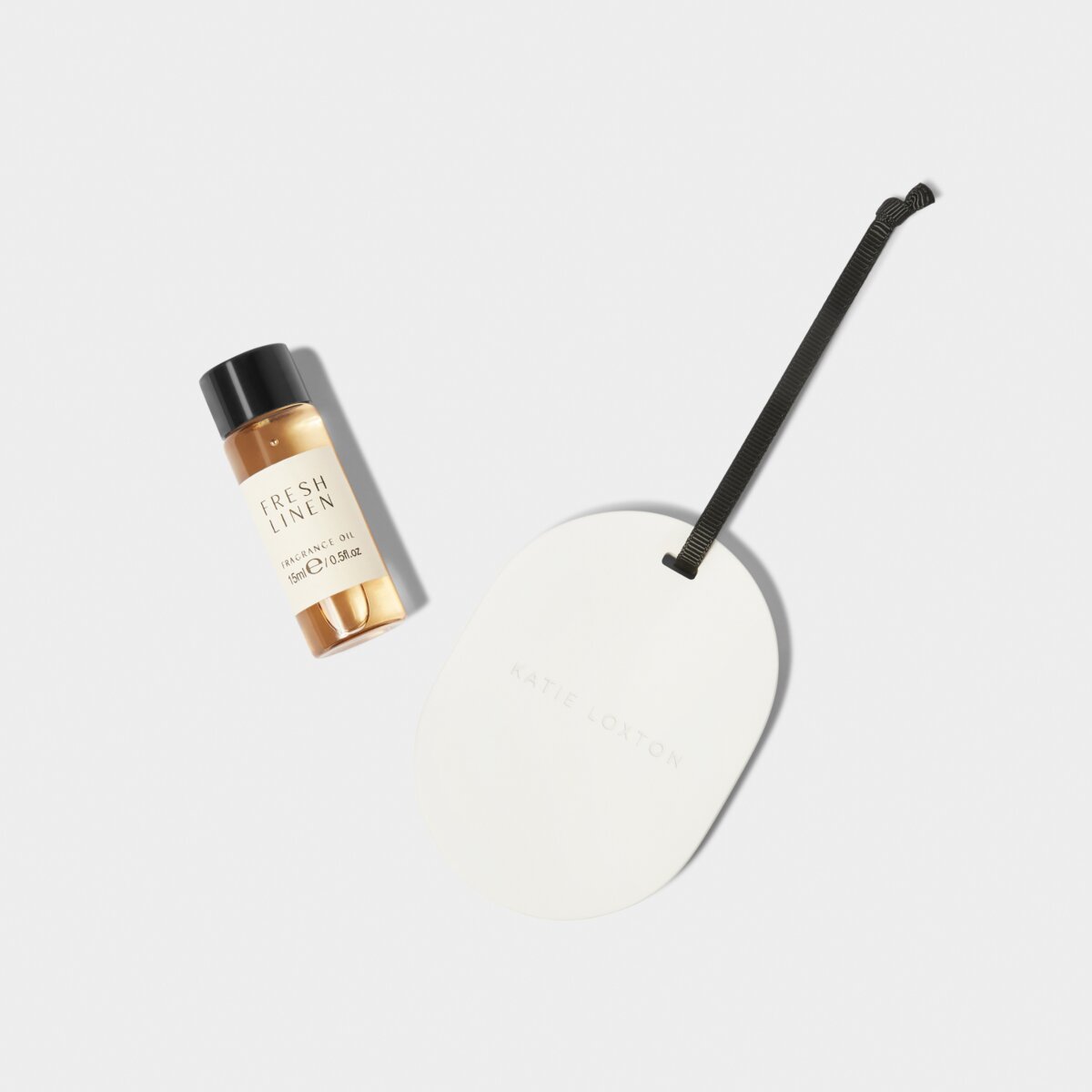 white cermaic diffuser lying next to fresh linen scented diffuser oil