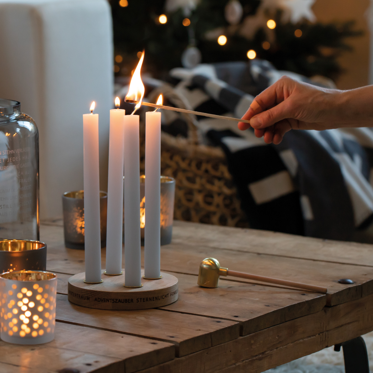 picture of hand holding a long match lighting candles in festive scene