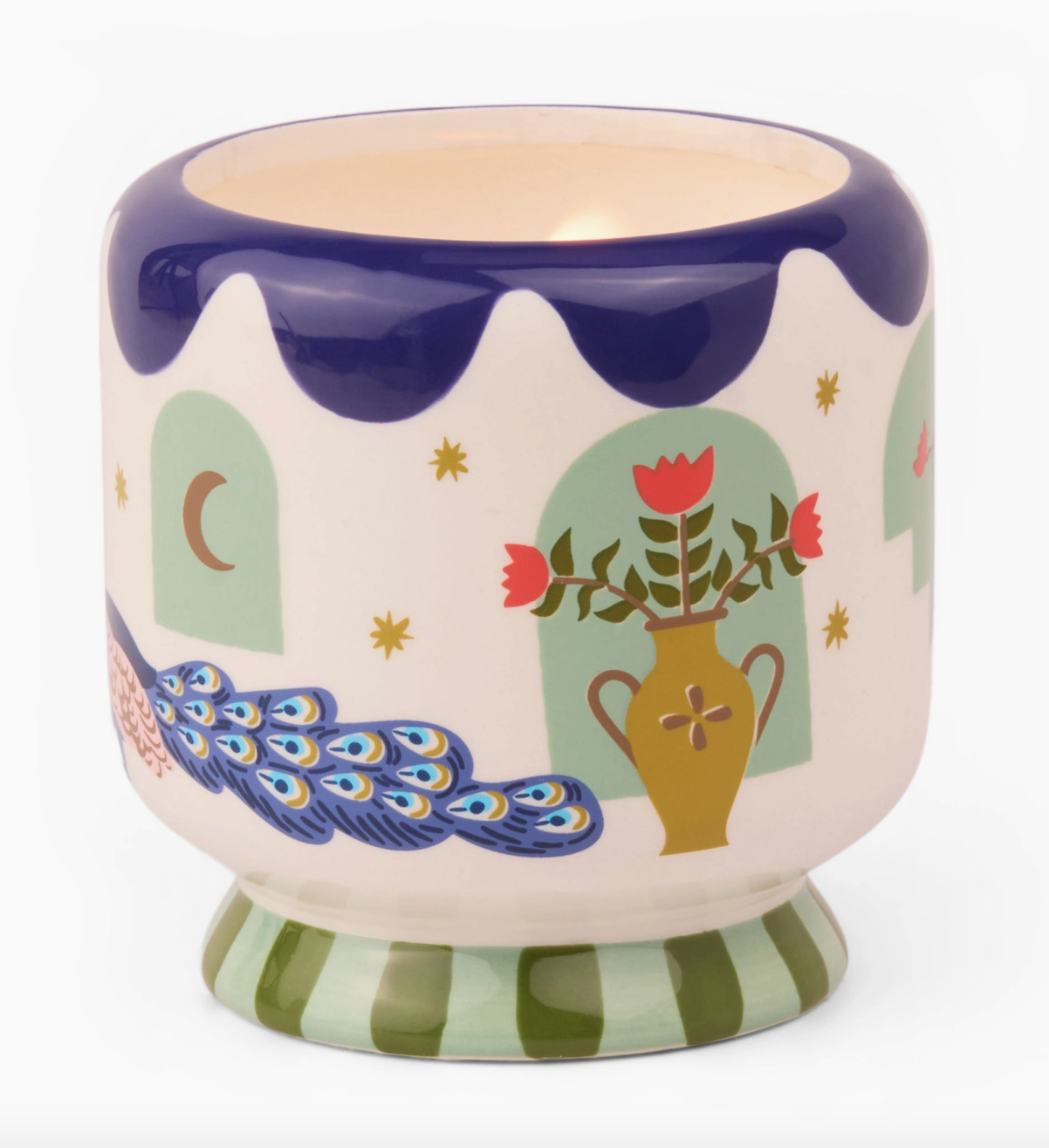 Scented candle in a cermaic pot decorated with a vase of flowers, stars a wavy blue rim around the top of the jar and a striped green line around the base.