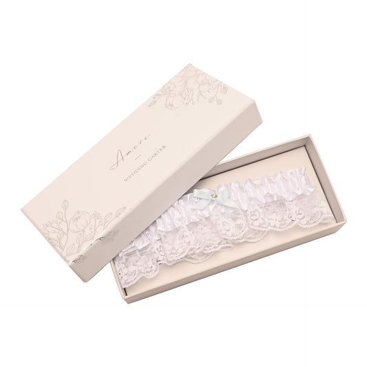 peachy pink gift box with floral detail contaning a white satin wedding garter with lace trim, small bow with crystal detail.