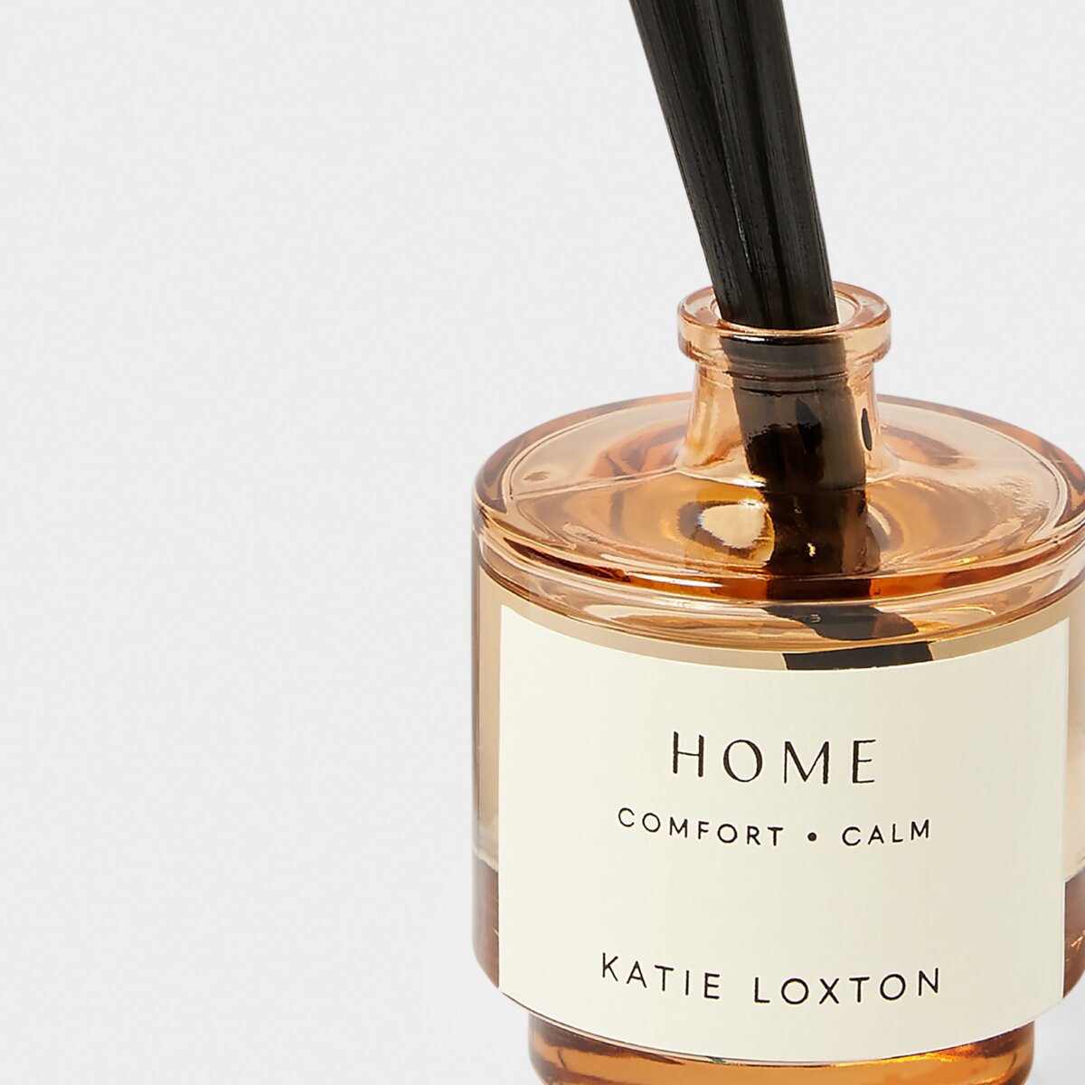 Close up of reed diffuser with amber glass  'Home' on the label
