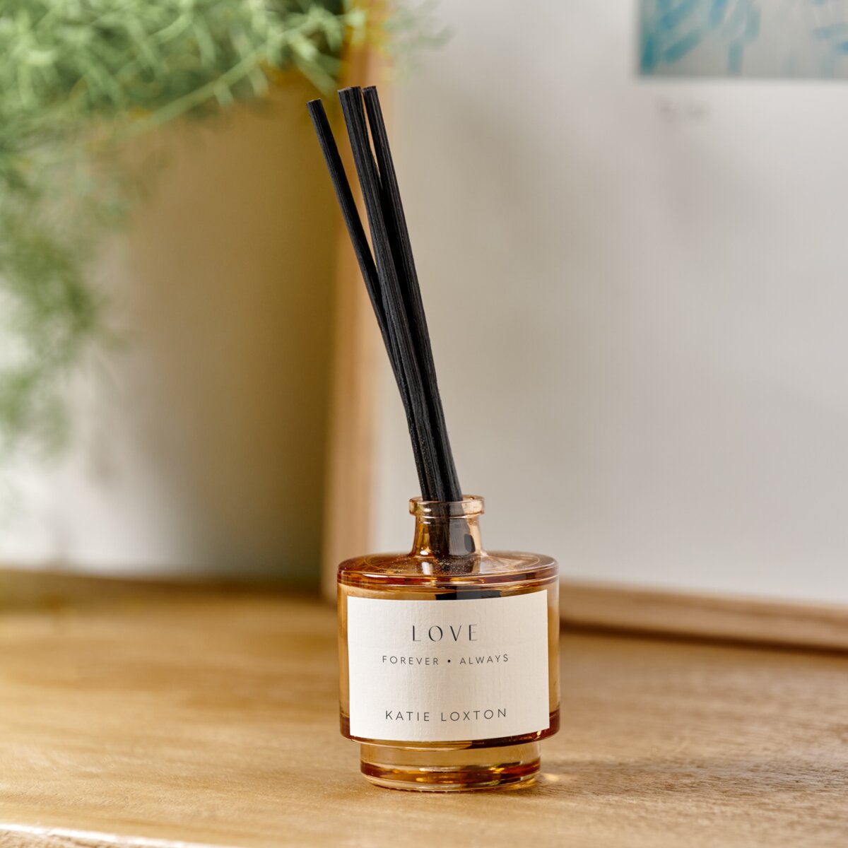 reed diffuser in an amber glass bottle with 'love' and black diffuser reeds