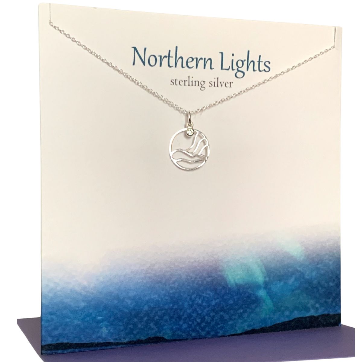Round silver pendant necklace with small crystal on a silver chain. Presented on a gift card that says 'Northern Lights Sterling Silver'. There is a depiction of the aurora borealis along the bottom of the card
