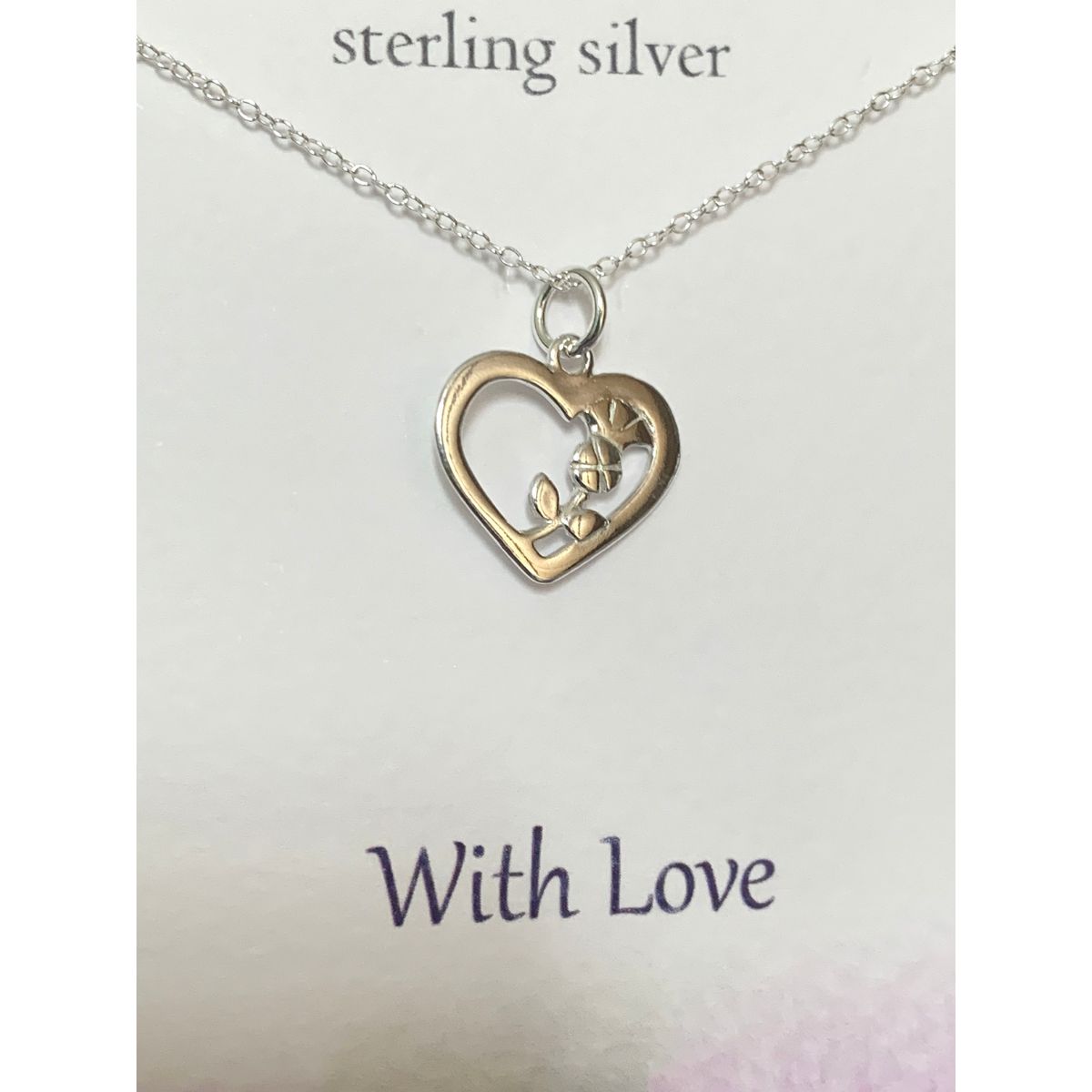 Close up of heart shaped silver pendant with entwined thistle on a silver chain. The presentation card reads Sterling silver With Love