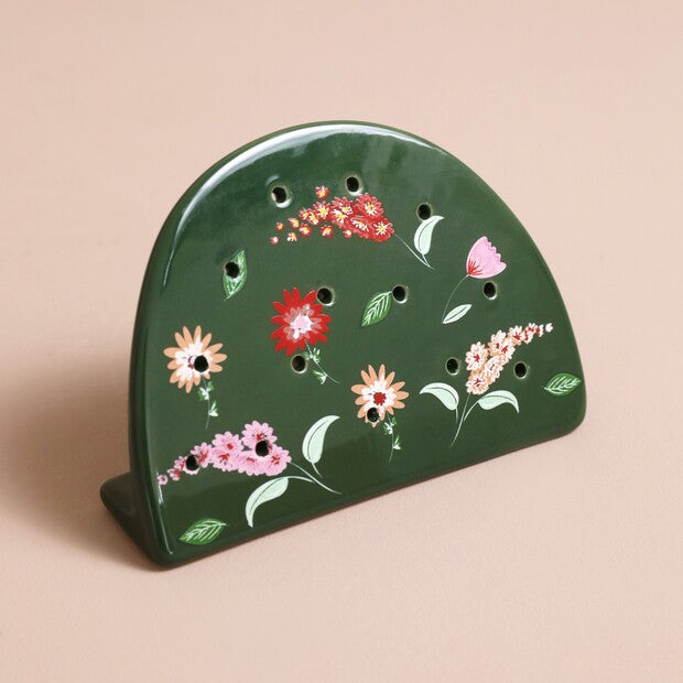 green semi-circular ceramic earring holder against a pink background