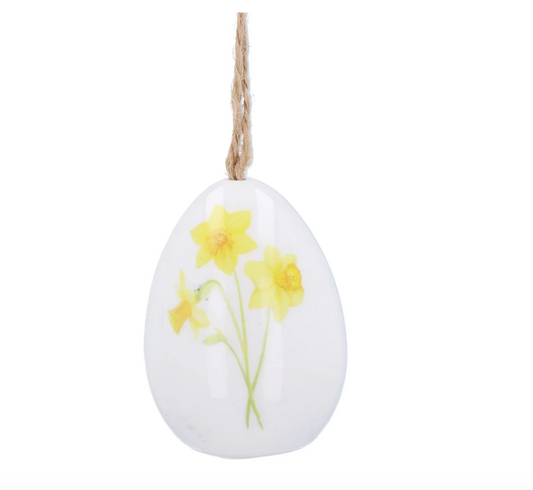white ceramic egg deocration featuring 3 yellow daffodils with green stems and a rustic brown hanging sring.