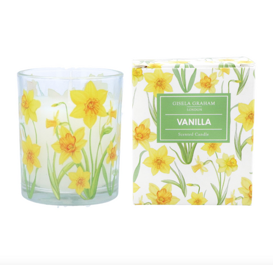 small scented candle in glass jar decoratd with yellow daffodils with green stems and leaves. The vanilla scented candle sits next to its presentation box which is decorated with a matching daffodil design