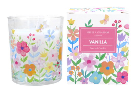 vanilla scented candle in a glass pot decorated with spring flowers in  pastel shades of pink, yellow and blue, It sits next to its gift box, which is decorated with the same floral pattern