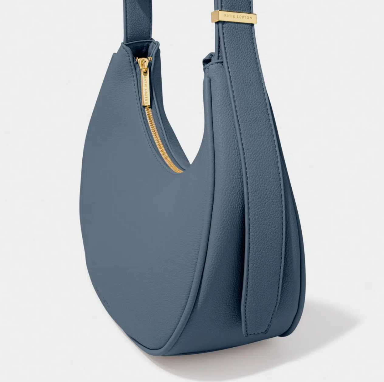 side view of navy blue scoop style handbag with gold zip against a white background