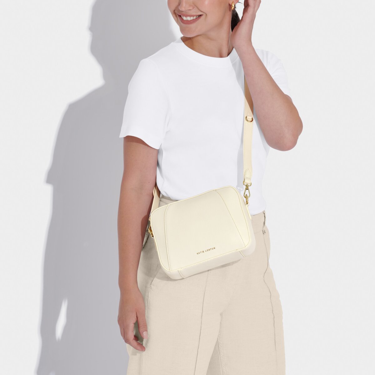 picture of a model wearing a white t-shirt and cream trousers wearing an off-white handbag in cross-body style