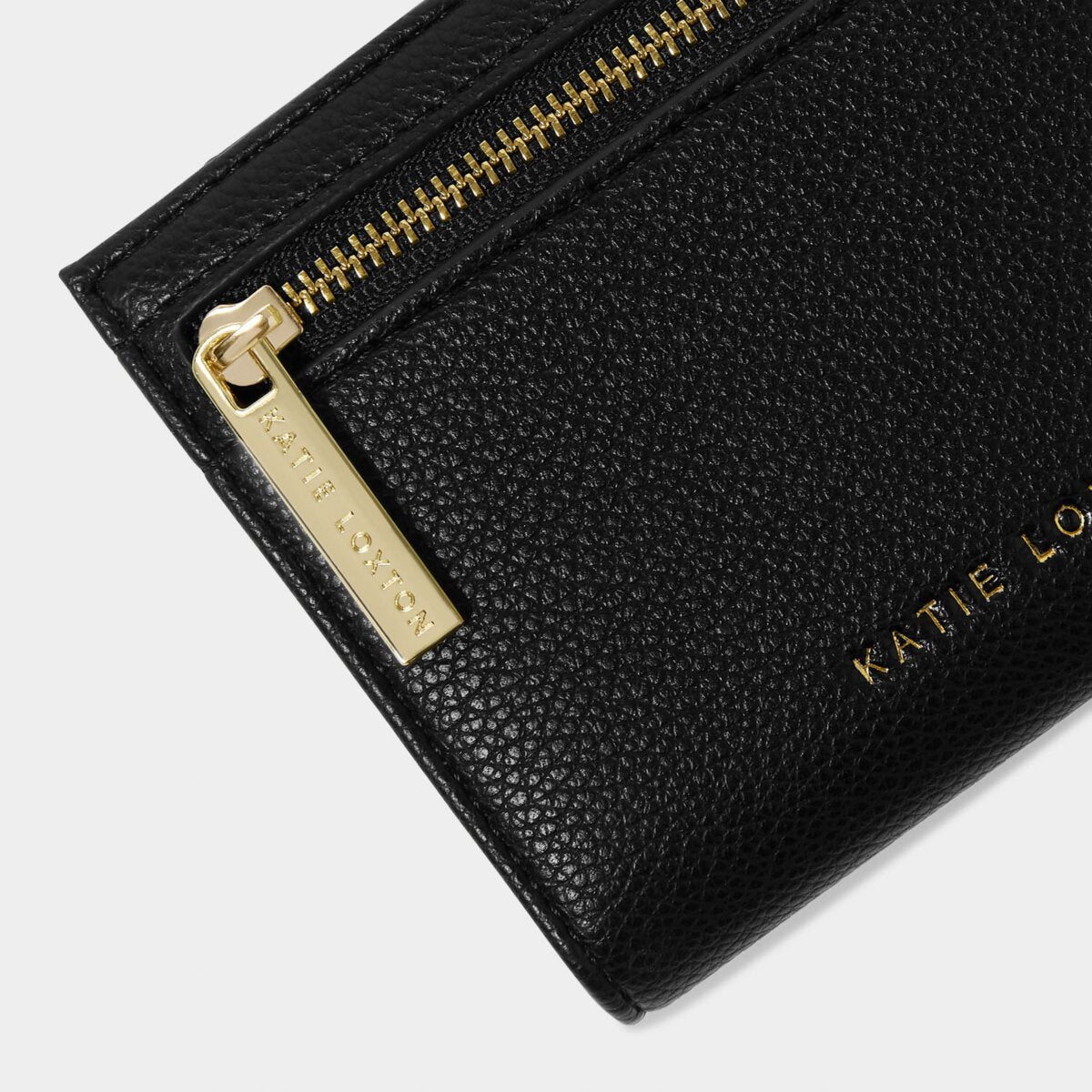 close up of black purse highlighting gold zipper which says Katie Loxton