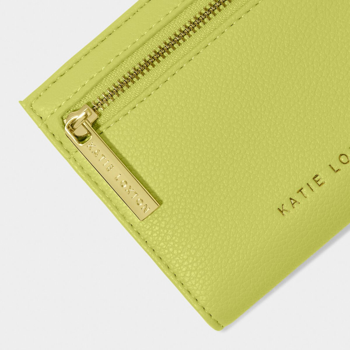 Close up of the Katie Loxton Jayde Purse in Lime Green, focussing on the zipper, which says Katie Loxton and the Katie Loxton gold foil print at the base of the purse.