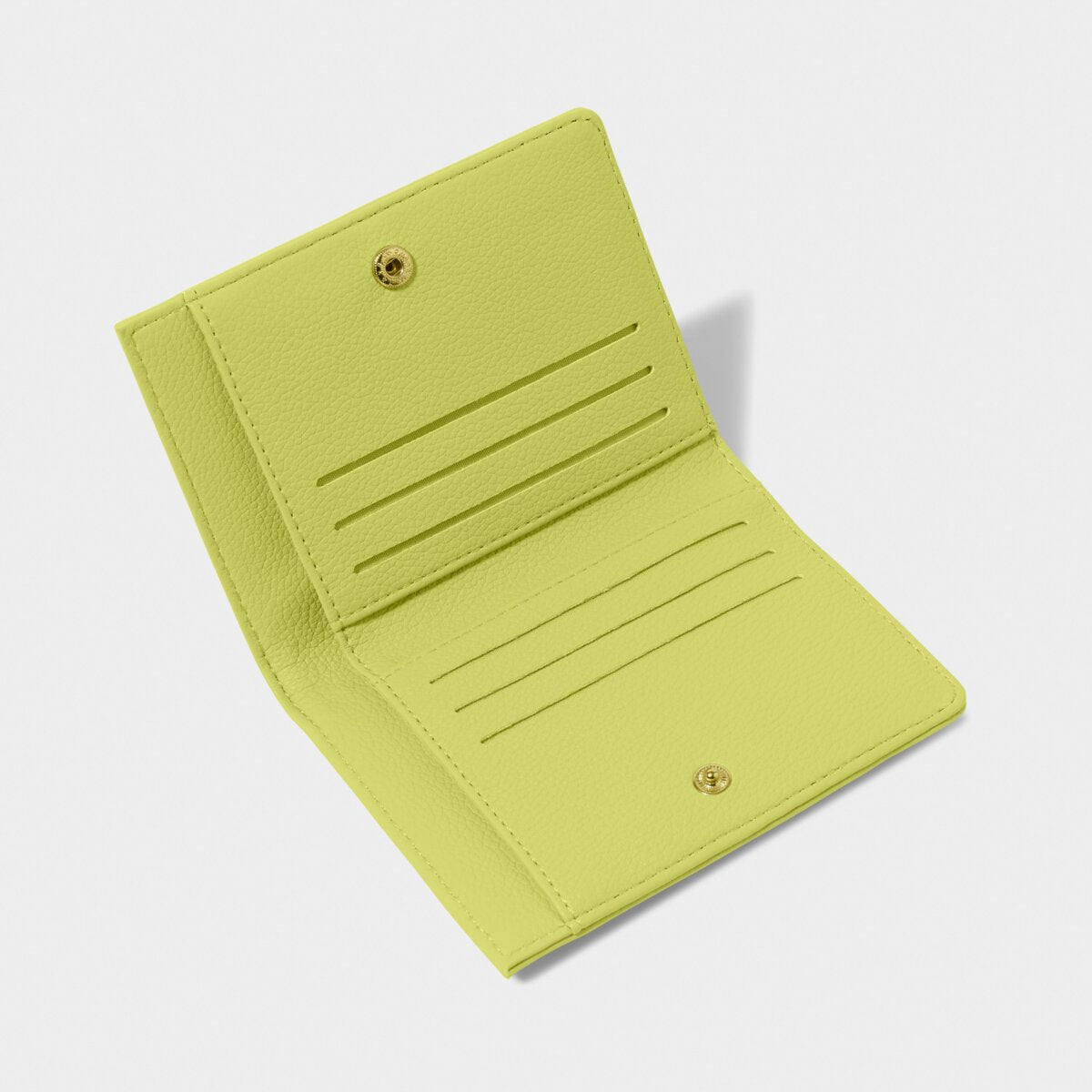 Picture of the inside of the Katie Loxton Jayde purse in lime green. It has six card slots and a section for cash notes. It has a gold popper fastener.