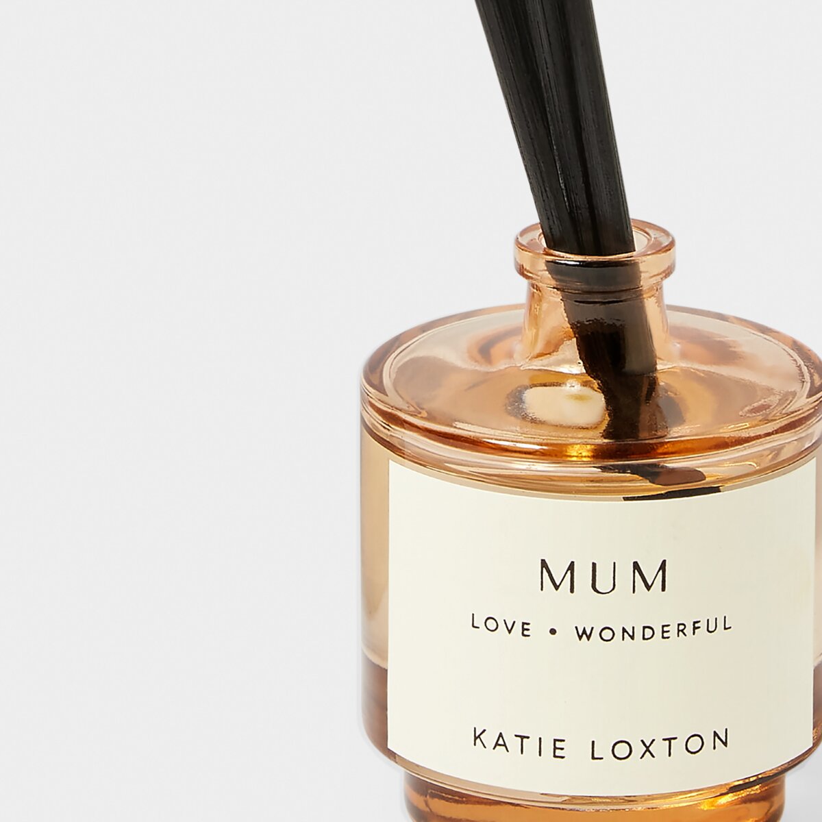 Close up shot of reed diffuser jar. Label on the jar says 'Mum', "love' and 'wonderful'