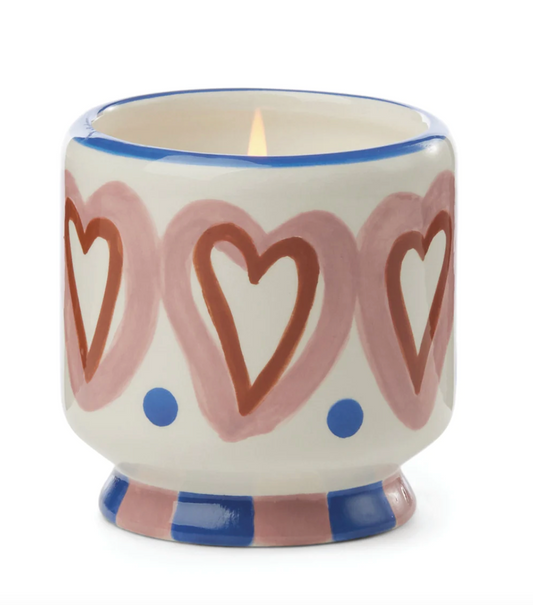 scented candle in a cermaic holder decoared with red and pink hearts with blue accents.