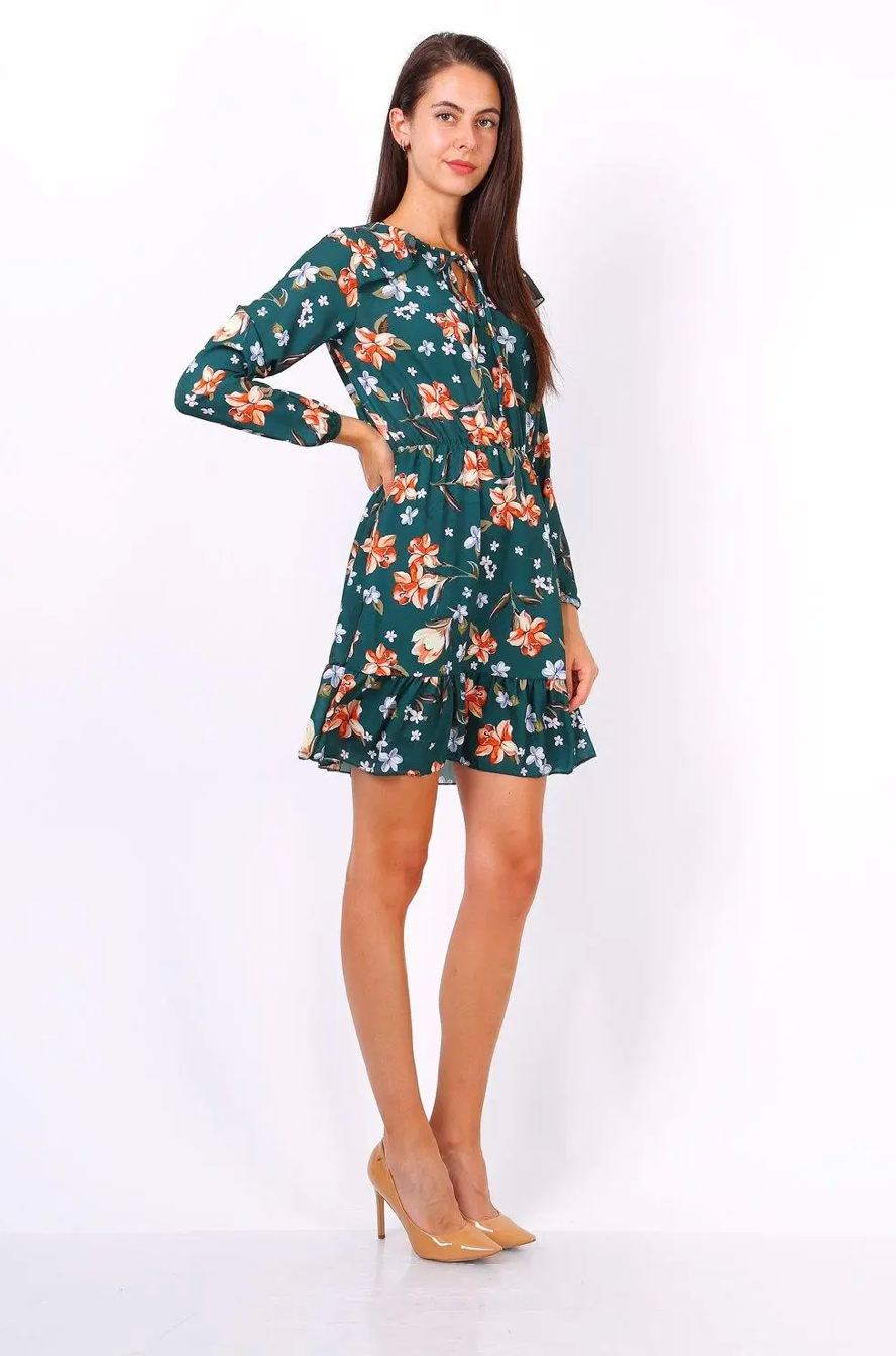 Model wearing green dress with orange and white floral print with nude shoes